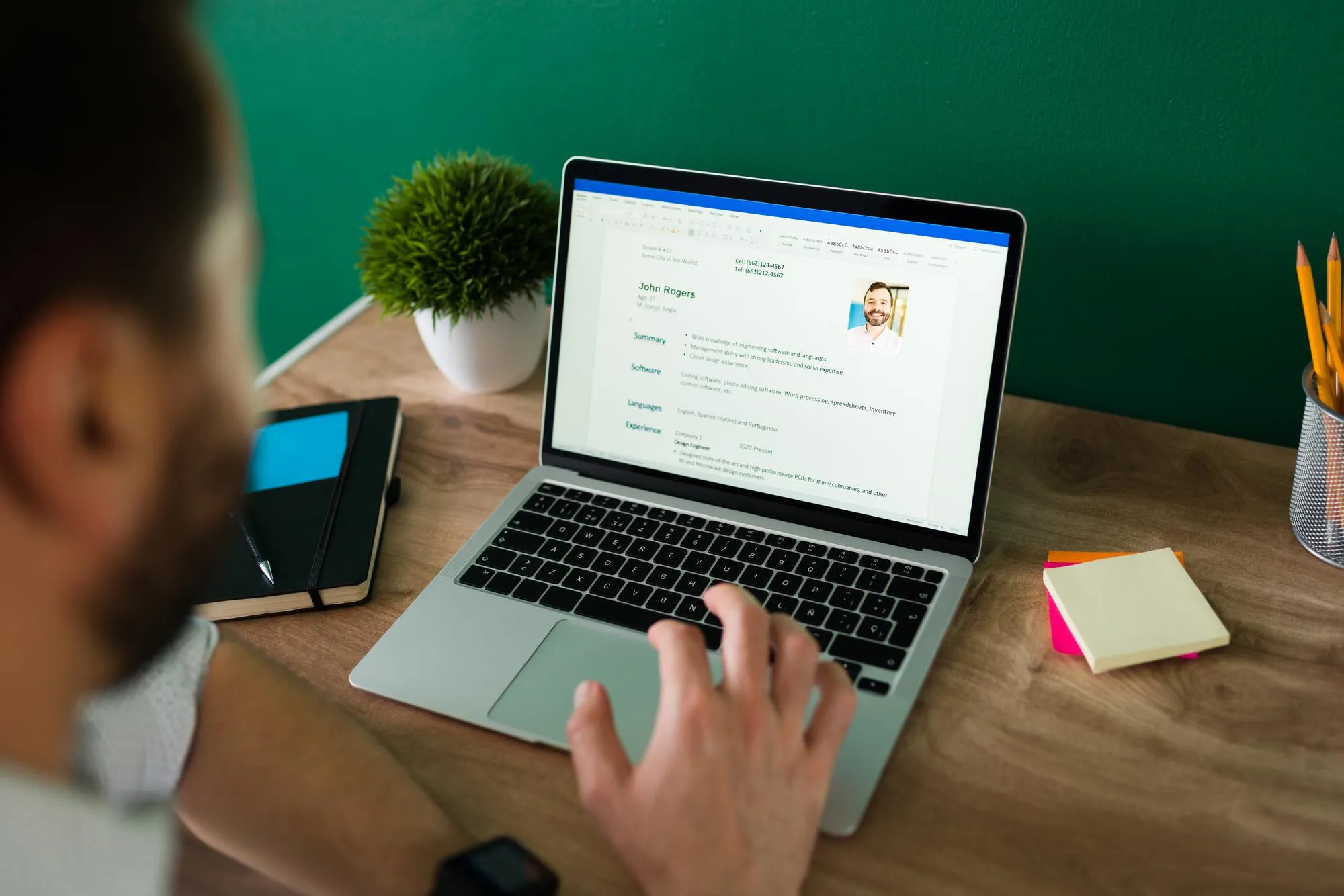 Rear view of an adult man searching for a new job and working on writing his resume on the laptop