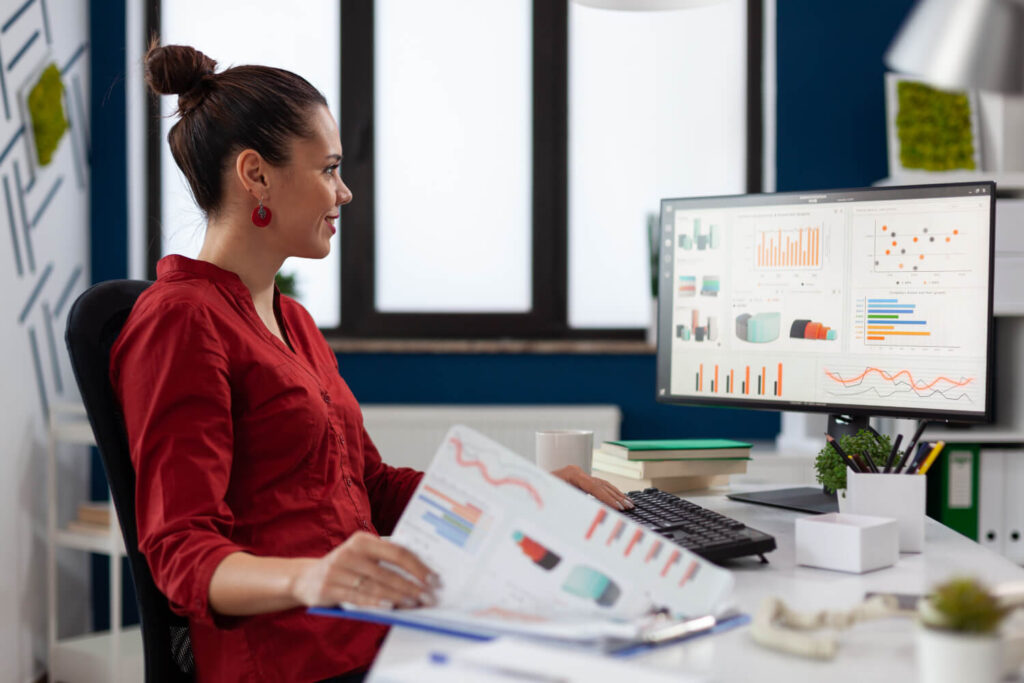 Businesswoman with clipboard sitting at desk in startup business office.